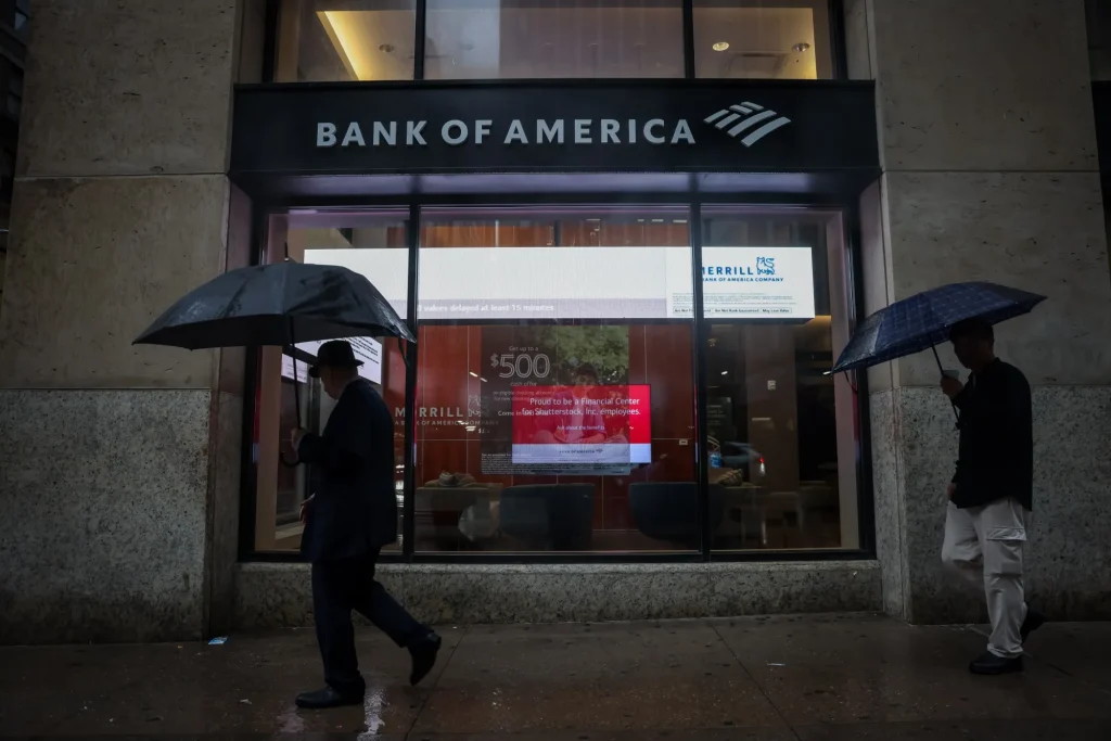Pedestrians with umbrellas outside a Bank of America branch